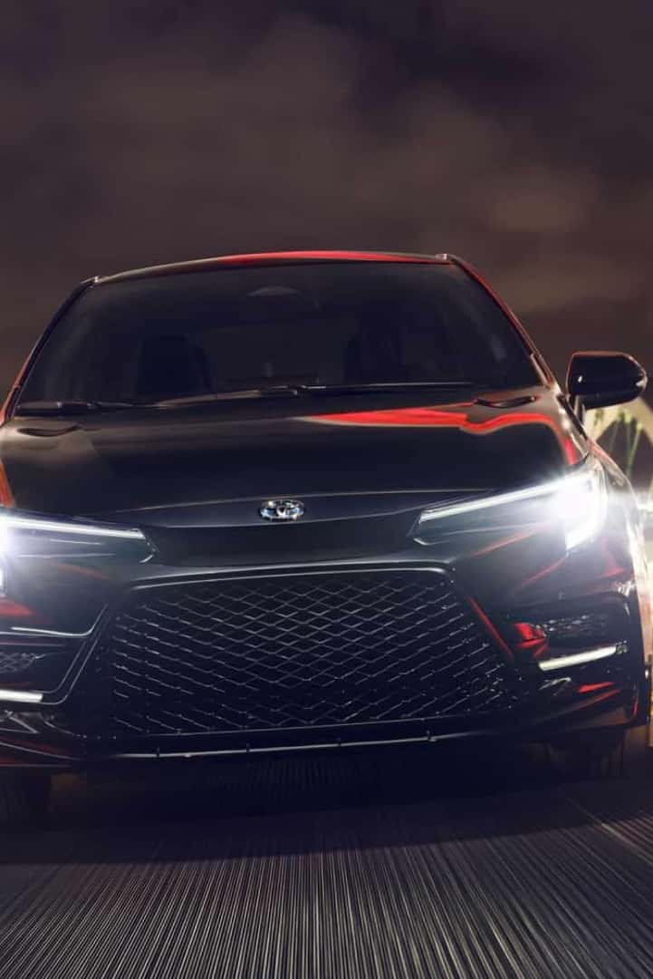 Front of Toyota sedan with headlights on