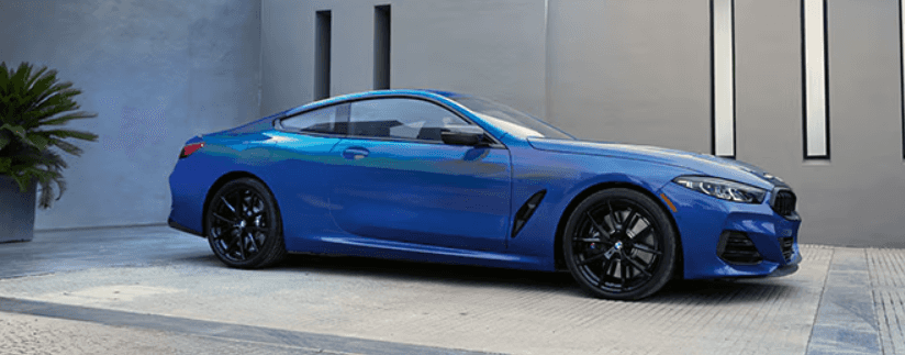 Blue BMW coupe parked outside a modern building, highlighting sleek design and performance styling at BMW of Northwest Arkansas