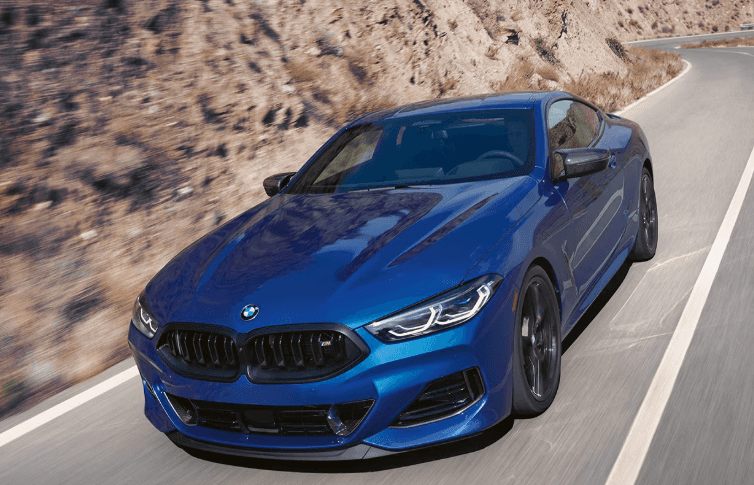 Blue 2026 BMW 8 Series Coupe on rocky road.