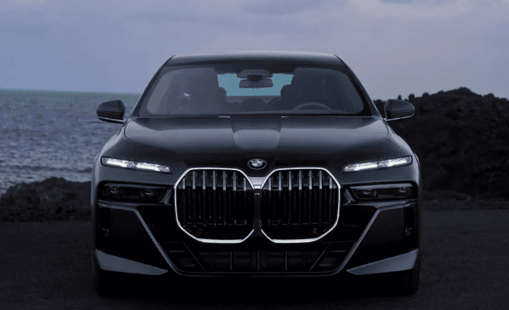 From view 2026 BMW 7 Series in front of beach coastline. 