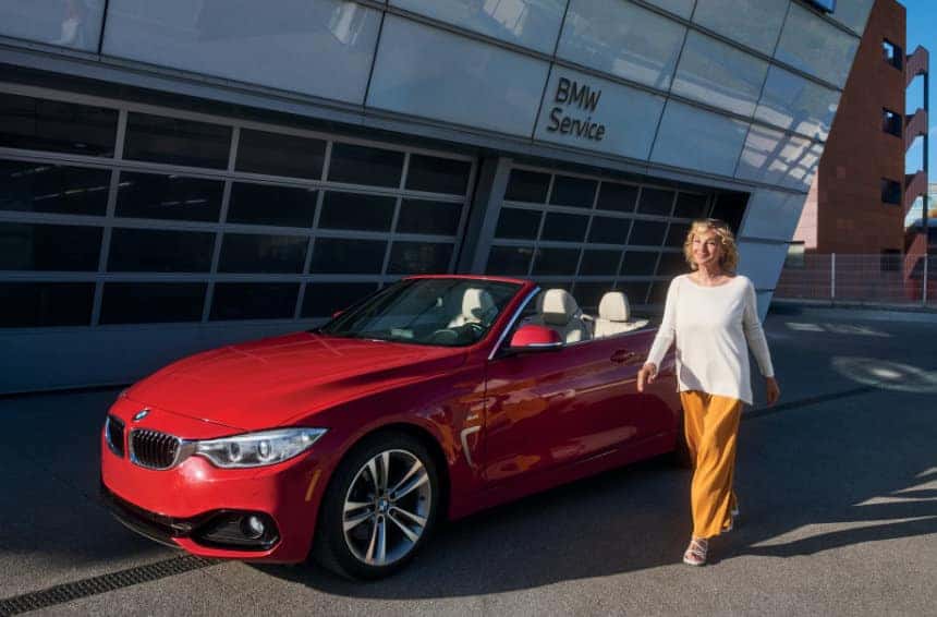 Woman walking past her CPO BMW in front of a BMW Service center