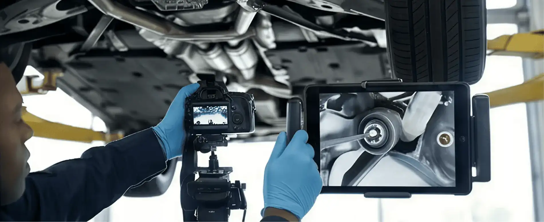 A BMW of South Atlanta service technician photographing the underside of a BMW on a lift, with a tablet showing the live image — illustrating multipoint inspection with photo and video documentation.