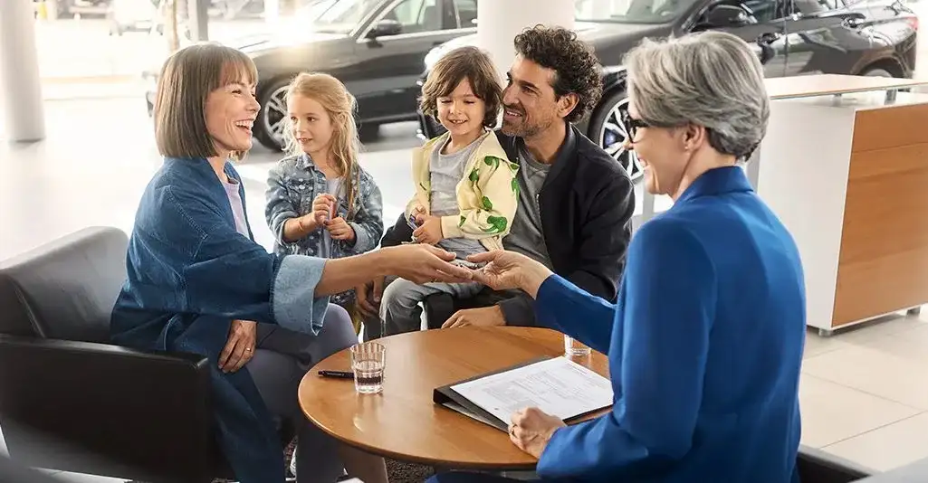 A family with two young children finalizing a BMW purchase at the dealership finance desk