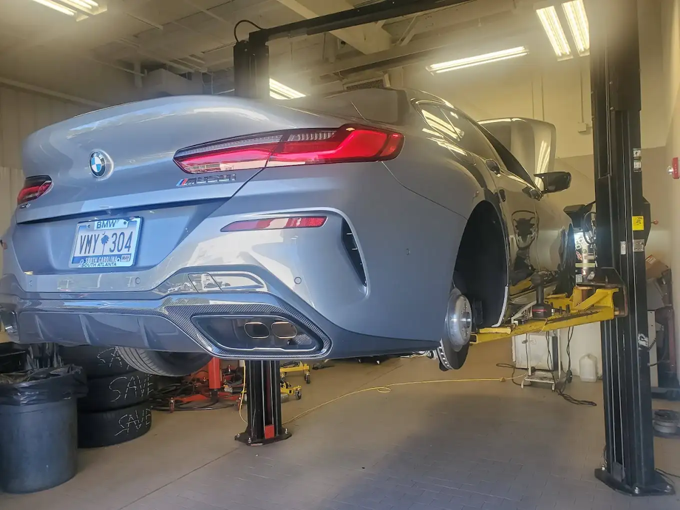 A BMW M850i up on a two-post lift in the BMW of South Atlanta service shop, mid-service
