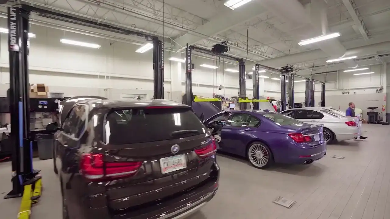 Inside the BMW of South Atlanta service shop in Union City — a BMW X5, an ALPINA B7, and a 5 Series on the lifts with a technician working