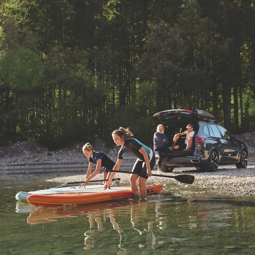 A family unloading paddleboards from their BMW SUV at the lake — the long-term, own-it lifestyle financing a BMW at BMW of South Atlanta is built around