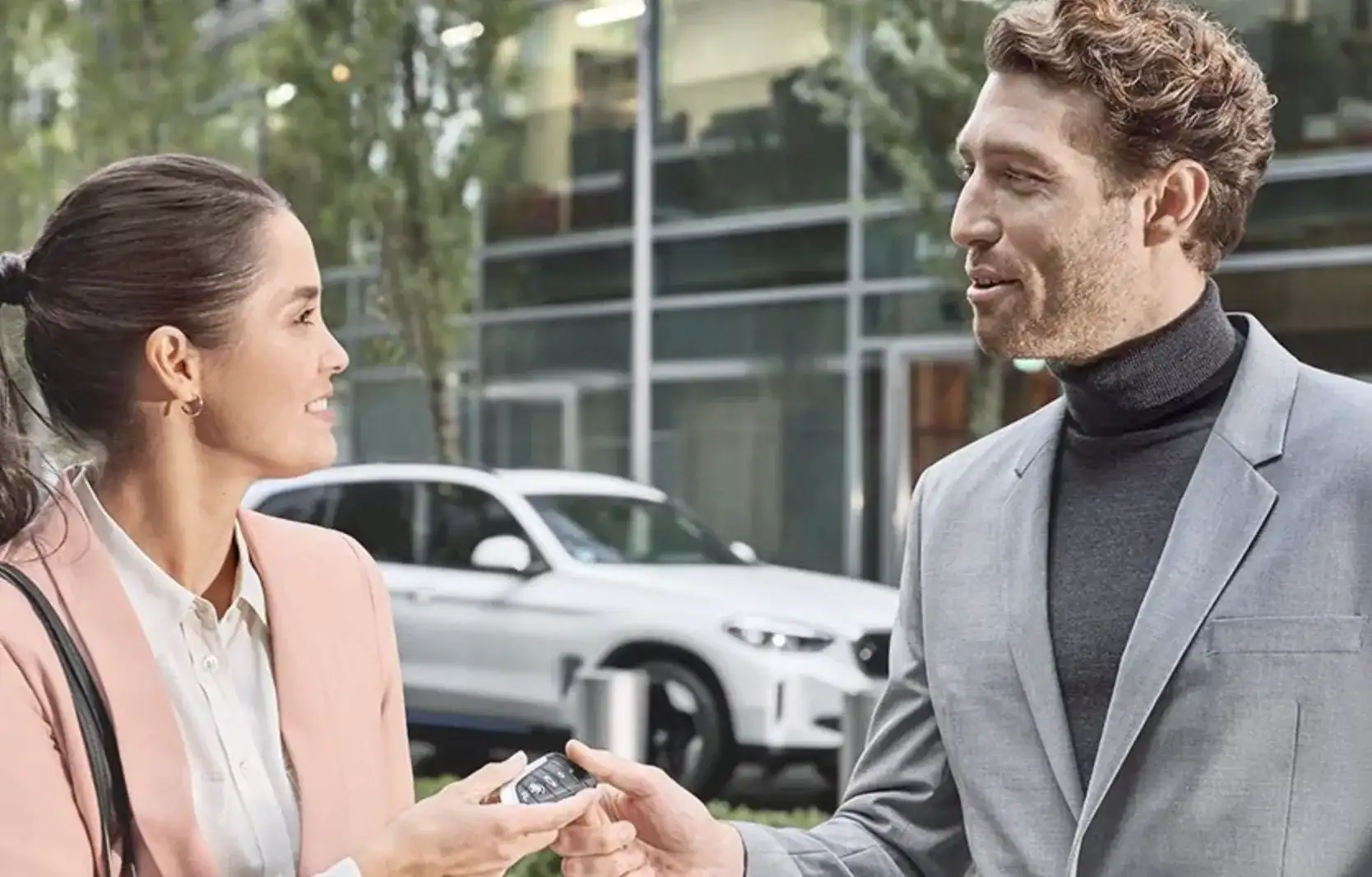 A salesperson hands over the keys to a smiling customer