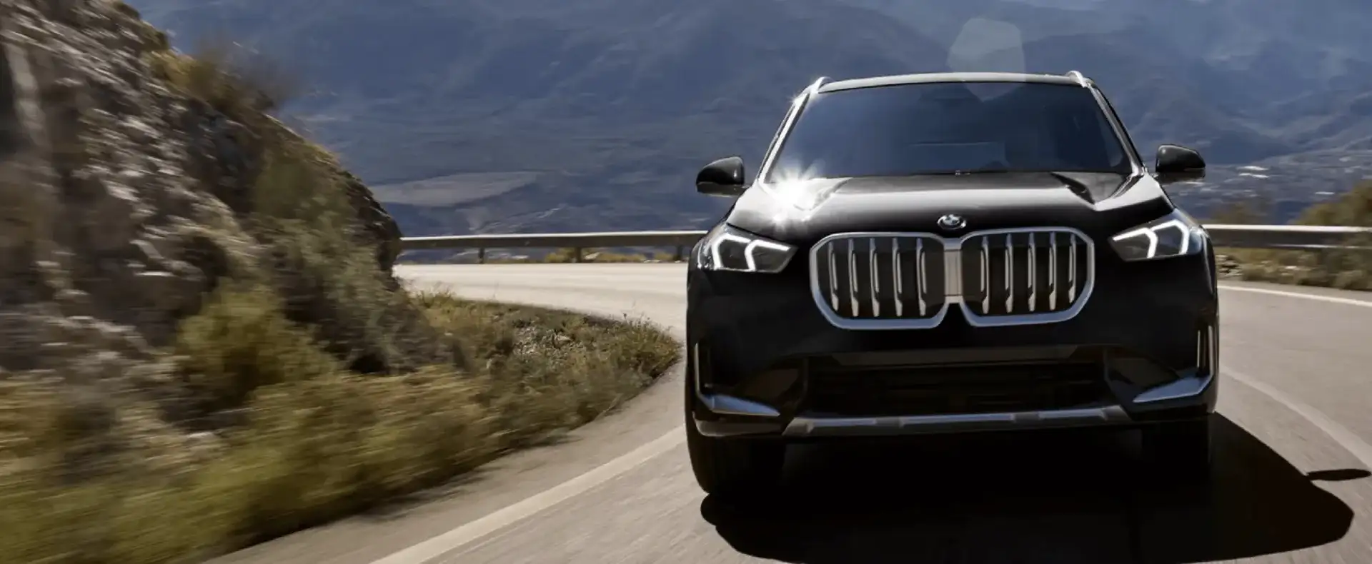 The 2026 BMW X1 driving on a winding mountain road with rocky cliffs