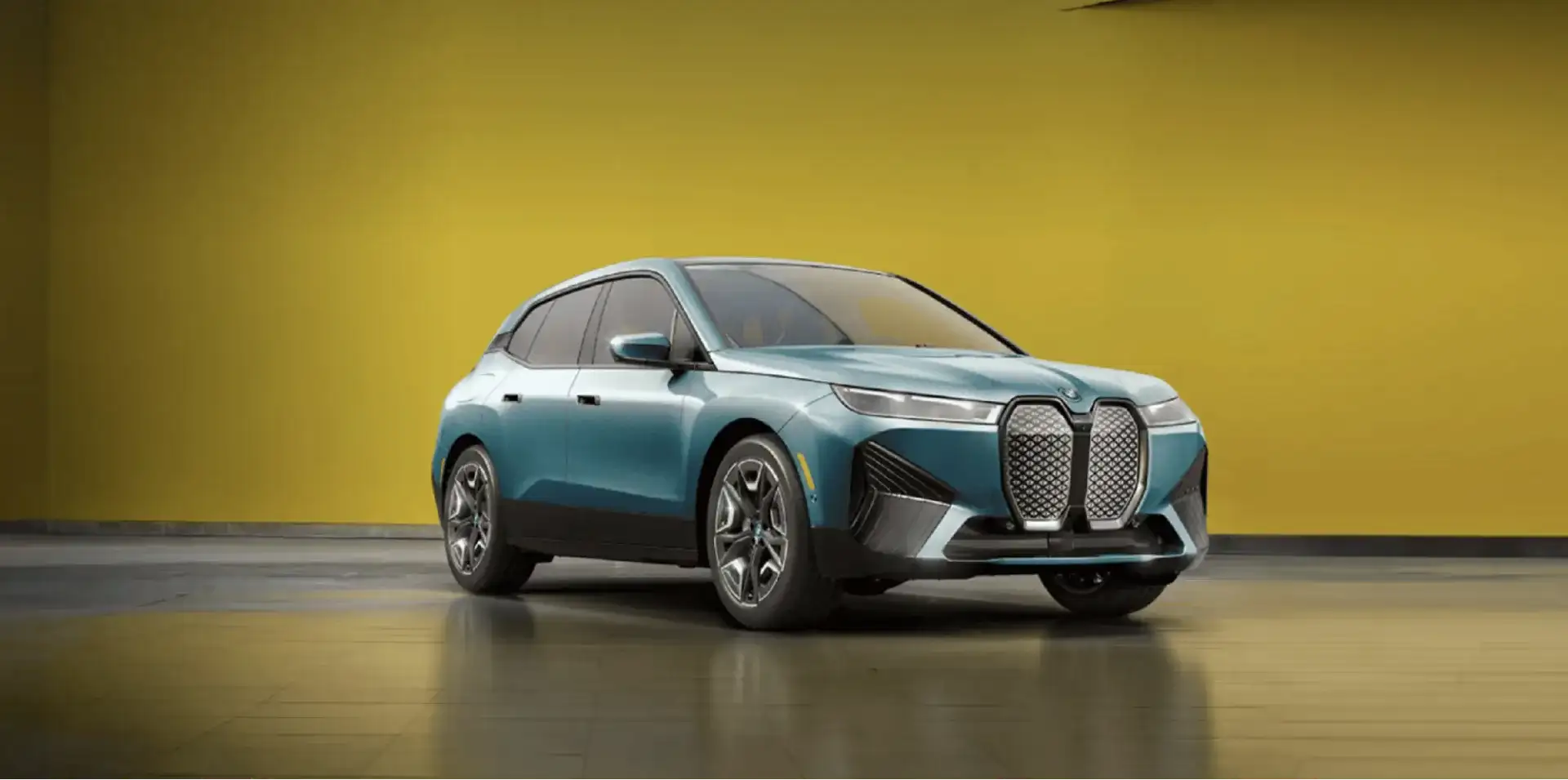 BMW iX electric SUV parked against a bright yellow studio backdrop