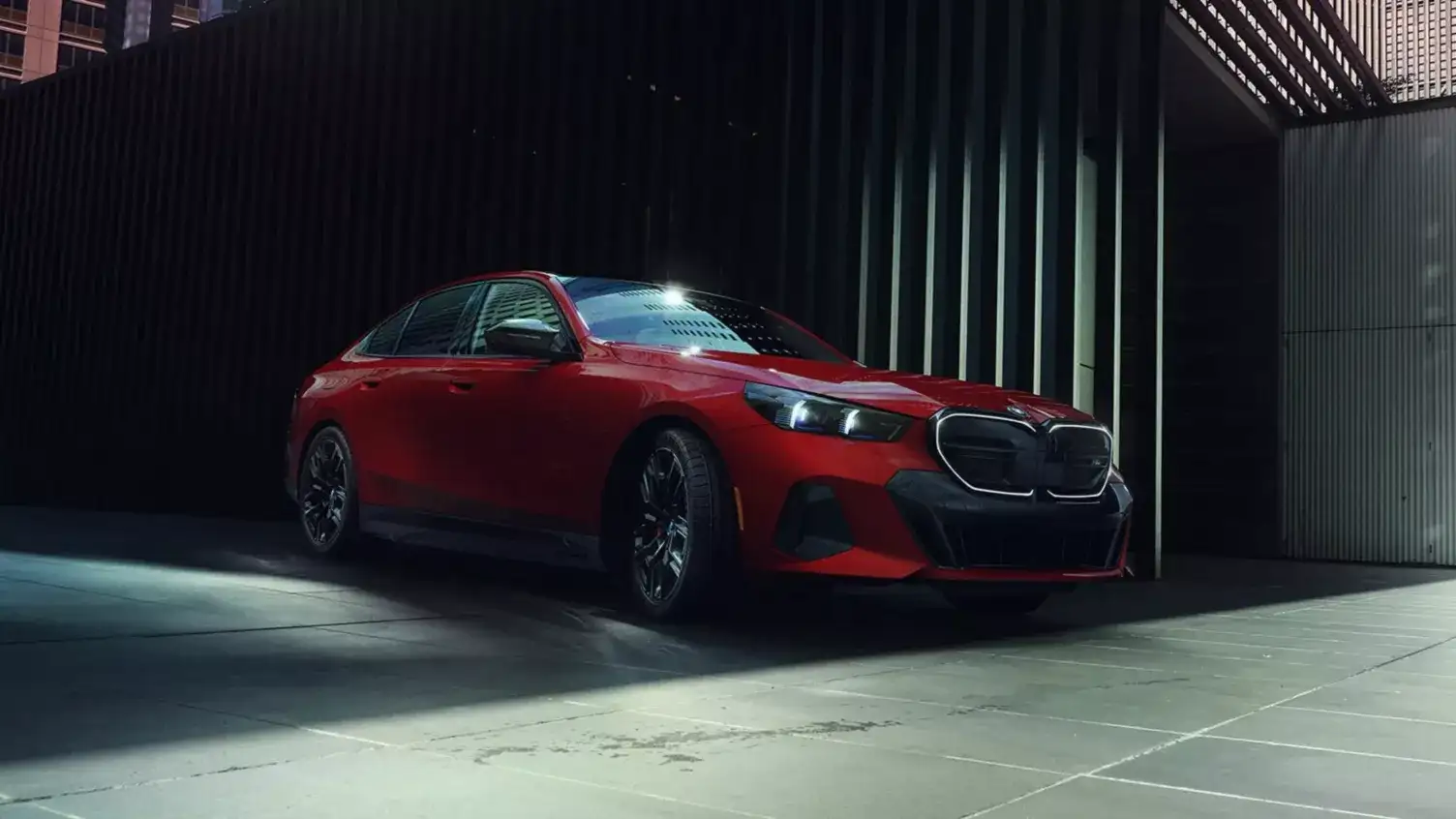 A red BMW 5 Series in a dark garage