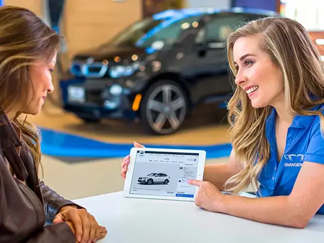 A BMW Genius walking a customer through vehicle details on a tablet in the showroom