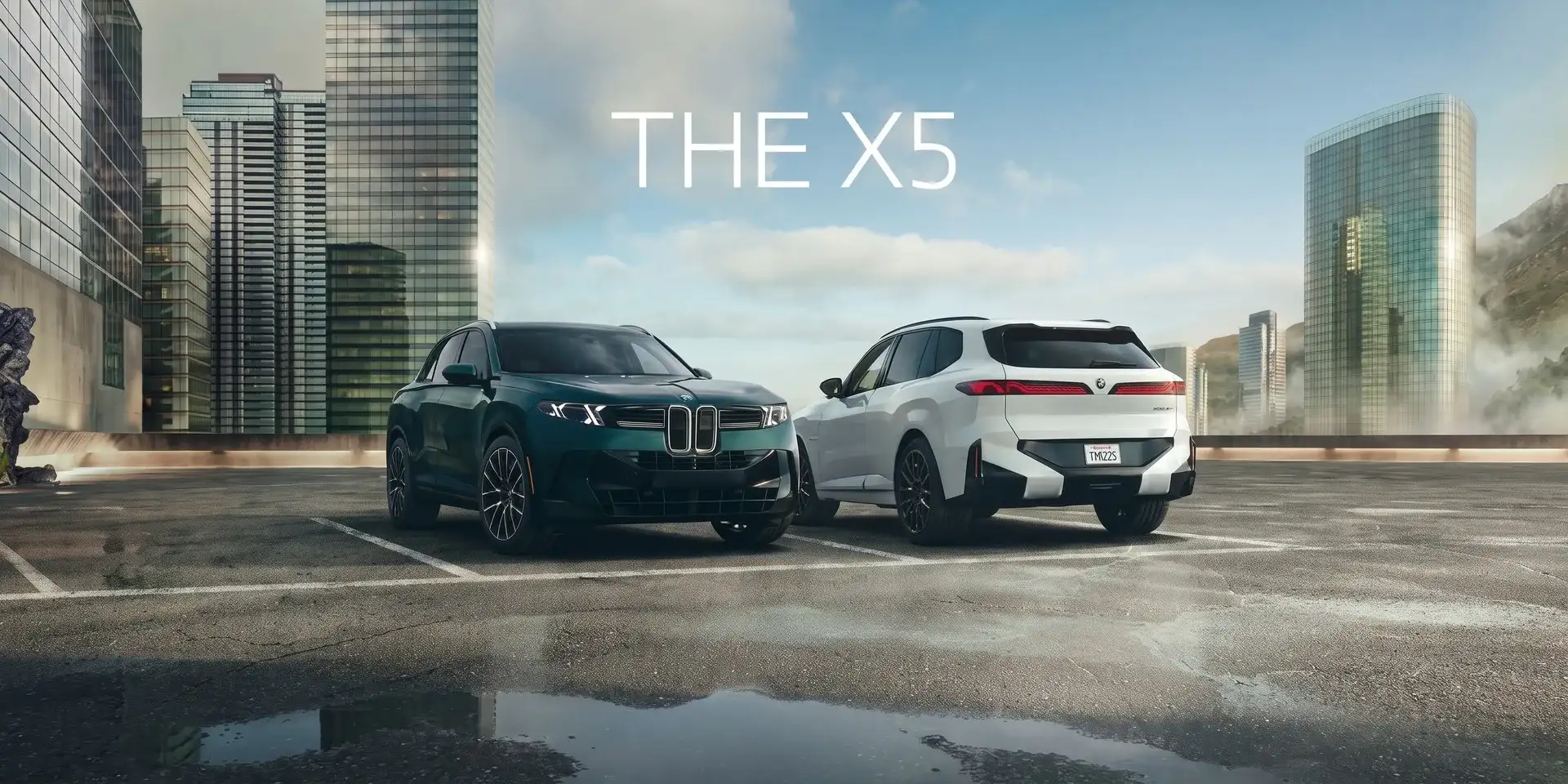 Two BMW X5s parked on wet concrete with a city skyline behind them