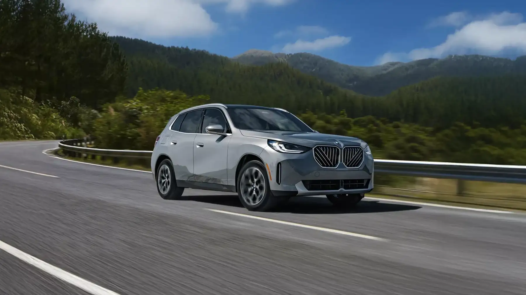 A silver BMW X3 driving on a mountain road