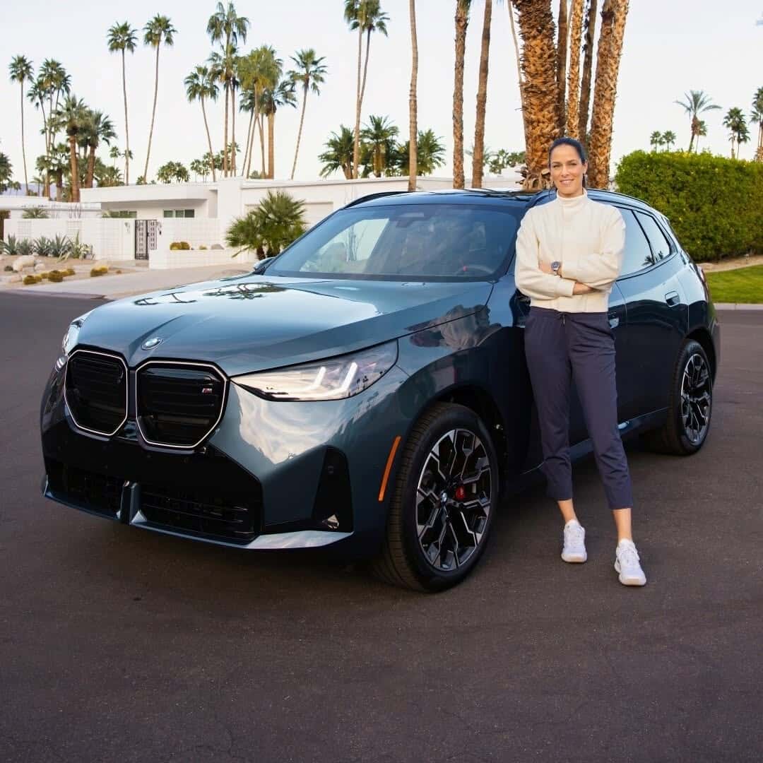 2026 BMW X3 centered on a sunlit street, front view under a bright sky