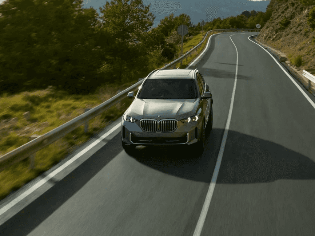 Silver BMW X5 driving a bright canyon highway, serviced and back on the road