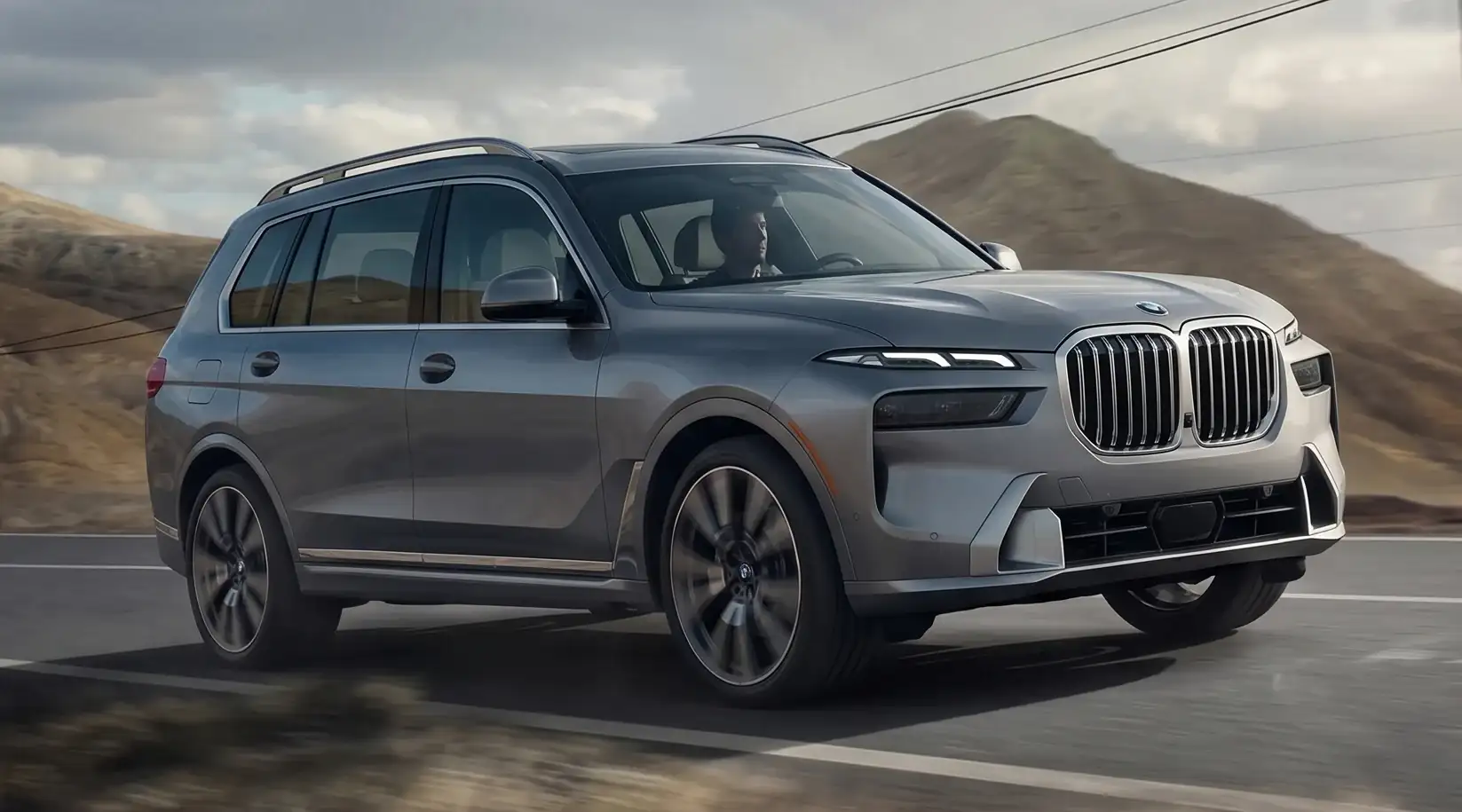 A BMW X7 driving on a coastal road