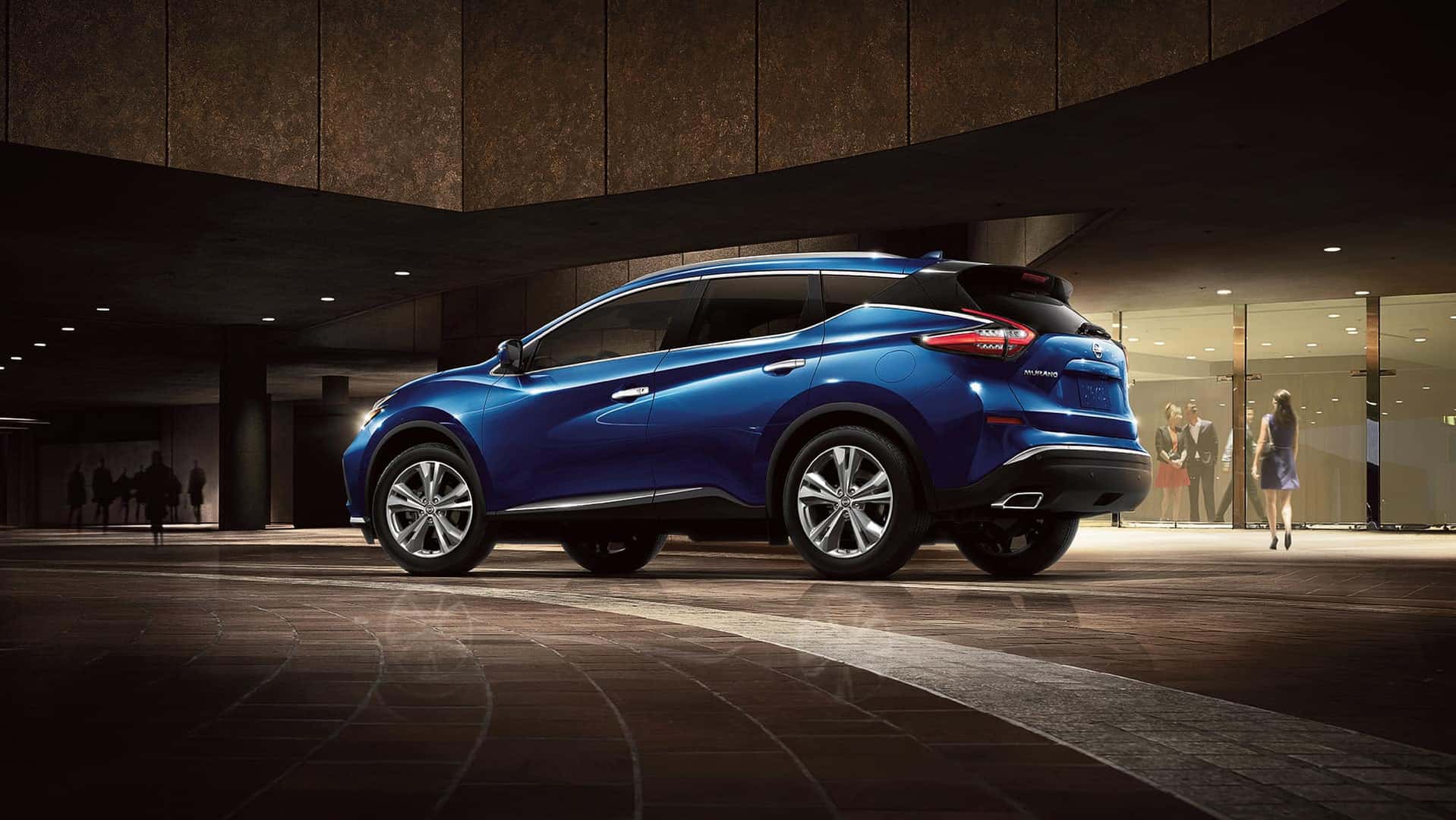 Nissan Boston is a Car Dealership near Boston MD | Blue MY20 Nissan Murano parked in front of dim lit luxury store front