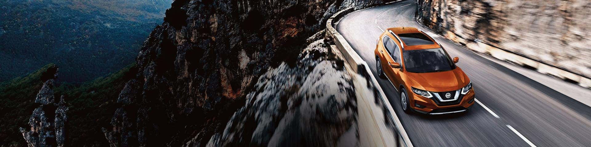 Boch Nissan South is a Family Owned Dealership near Attleboro, MA | Orange MY20 Nissan Rougue driving on mountain road