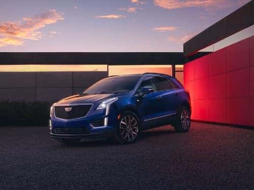 2024 Cadillac XT5 parked outside a modern building at dusk with headlights on