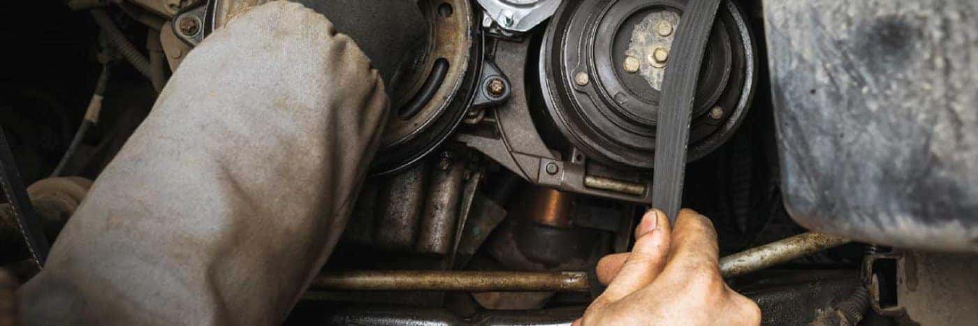 close up view of a service tech messing with a vehicle's belt system