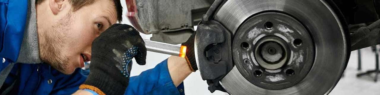View of a service tech inspecting brake pads on a vehicle