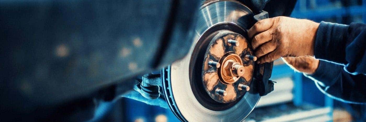 View of a service tech inspecting a vehicle's brake rotor