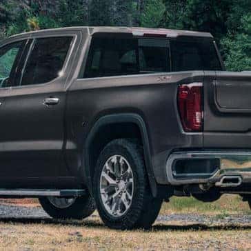 GMC Sierra parked on side of a road with forest scenery