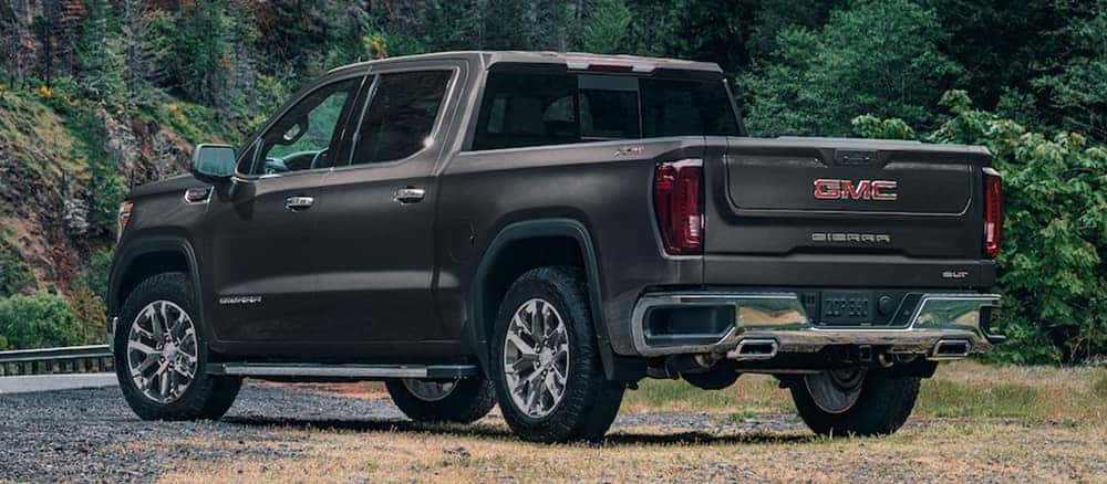 GMC Sierra parked on side of a road with forest scenery
