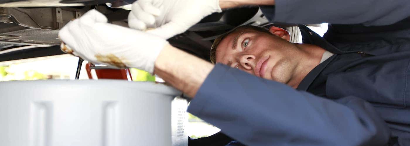 mechanic laying under car draining oil