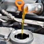 Mechanic in Greenfield, WI pouring oil into a vehicle during an oil change near milwaukee