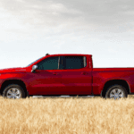 Man walking by a red Silverado truck in a field of wheat