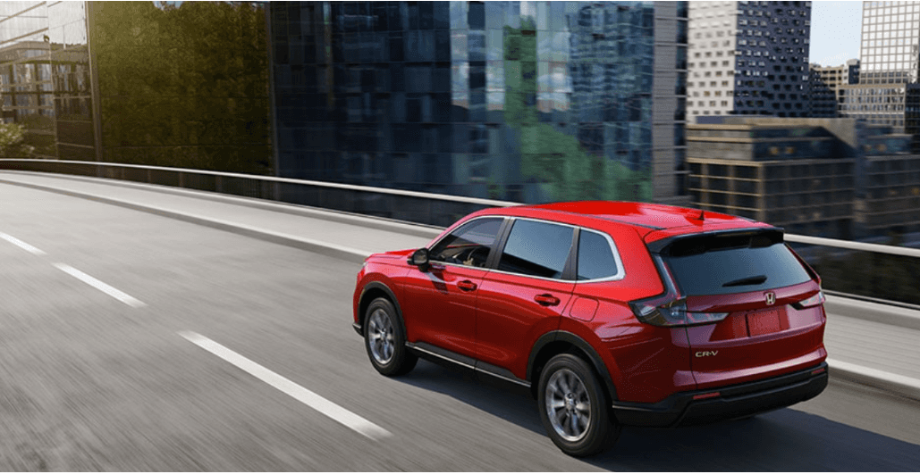 Red 2023 Honda CR-V driving down a city street