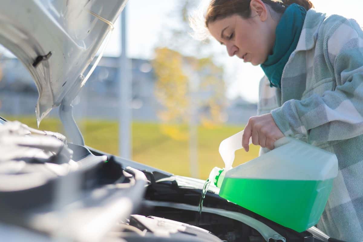 A woman refilling her vehicle's wiper fluid in the cold