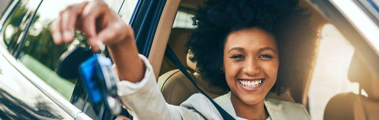 A happy customer driving away in a new Honda vehicle from Nalley Honda Brunswick with a scenic Brunswick, GA backdrop.
