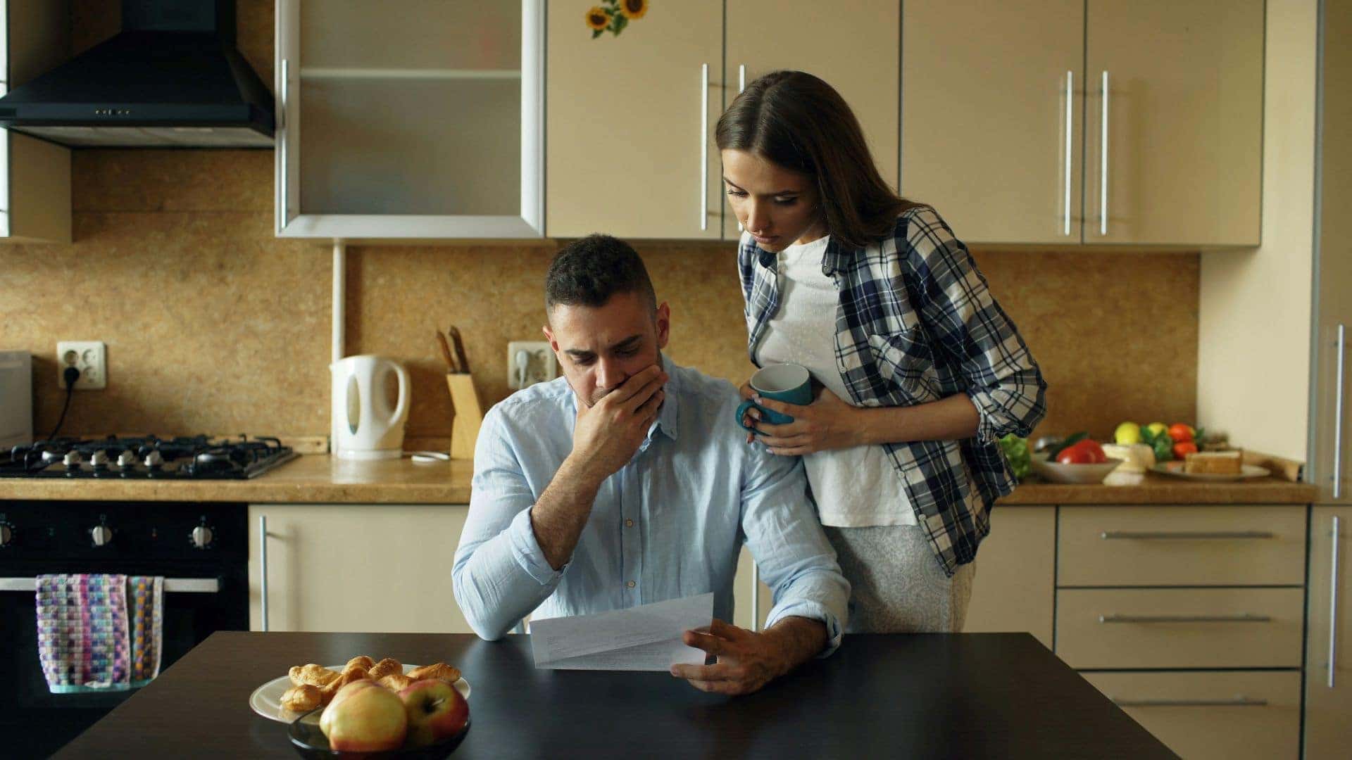 Worried couple looking at bill in kitchen