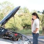 woman calling for help by broken down car