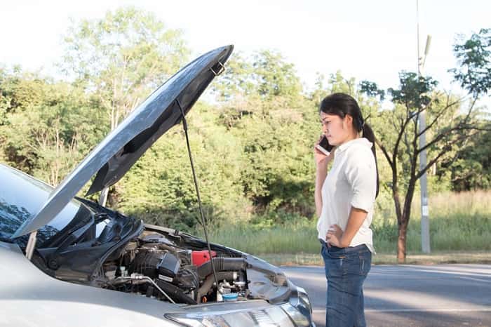 woman calling for help by broken down car