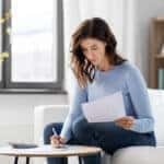 accounting, taxes and finances concept - young woman with papers and calculator at home