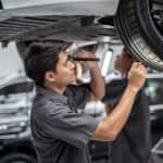 Asian mechanic Checking and torch tire in maintainance service center which is a part of showroom, technician or engineer professional work for customer, car repair concept