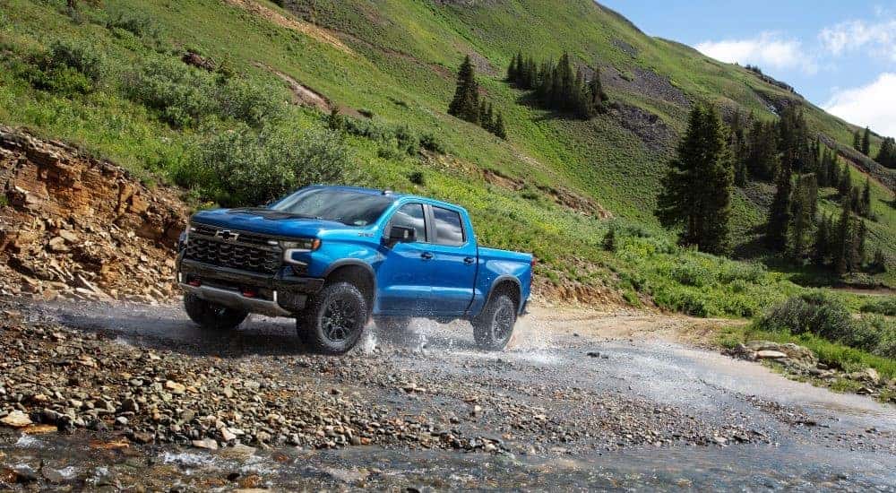 A blue 2024 Chevy Silverado ZR2 driving to a Chevy dealer.