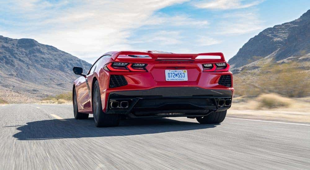 A red 2020 Chevy Corvette Stingray driving on a cloudy day.