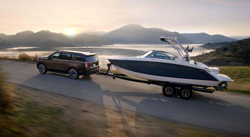 A grey 2021 Chevy Tahoe towing a boat at sunrise.