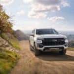 A white 2021 Chevy Tahoe Z71 on a dusty trail after leaving a used Chevy dealer.