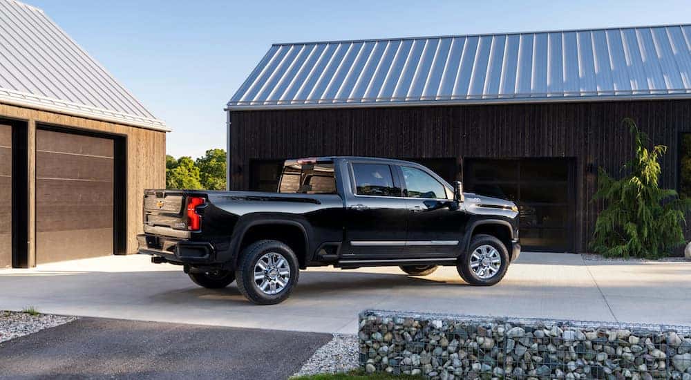 A black 2024 Chevy Silverado 2500 HD High Country parked near a garage.