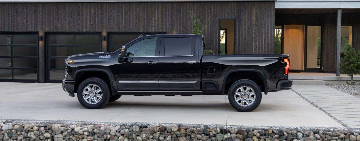 A black 2024 Chevy Silverado 2500HD High Country parked in front of a garage.