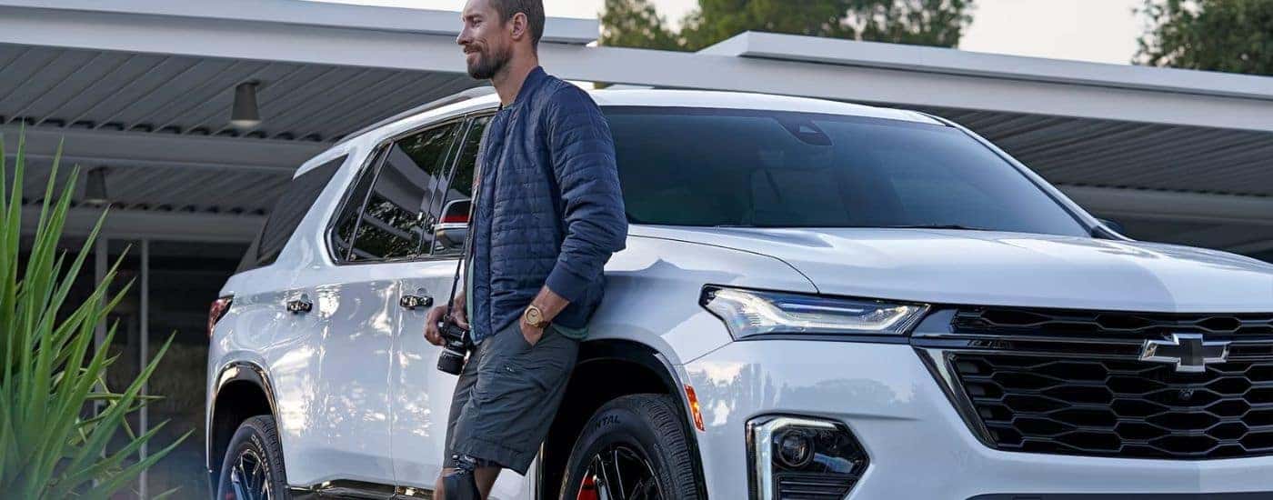 A person leaning against a white 2023 Chevy Traverse Redline.