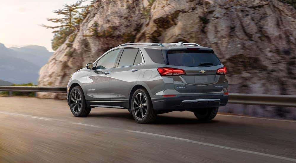 A grey 2024 Chevy Equinox Premier driving around a mountain bend.
