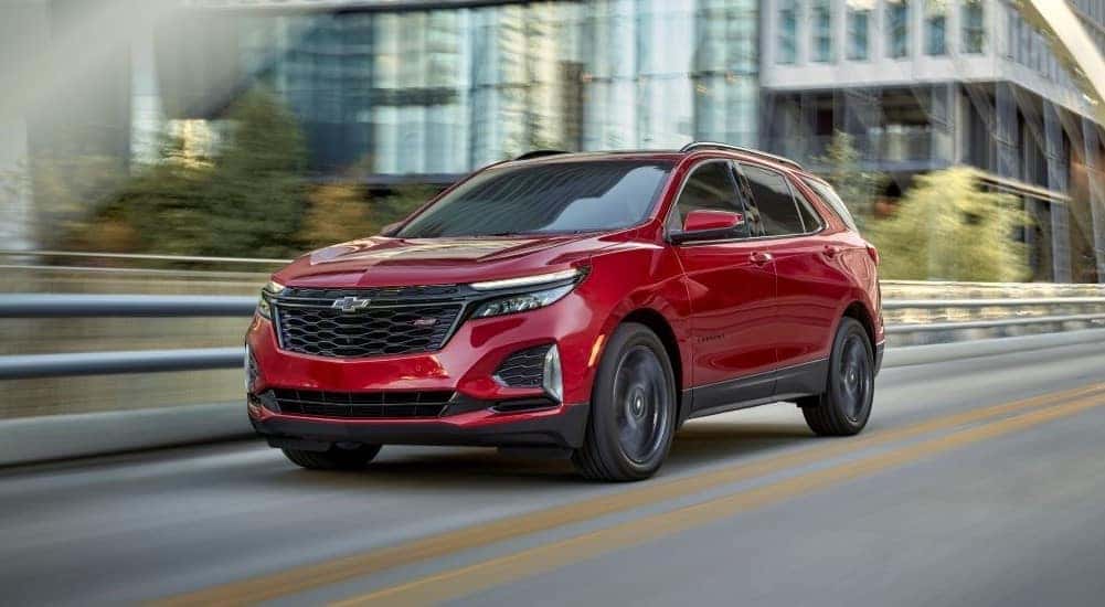 A red 2024 Chevy Equinox RS driving across a bridge.