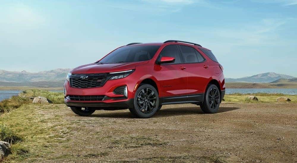 A red 2024 Chevy Equinox RS for sale parked near a lake.
