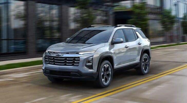 A white 2025 Chevy Equinox driving in a city.